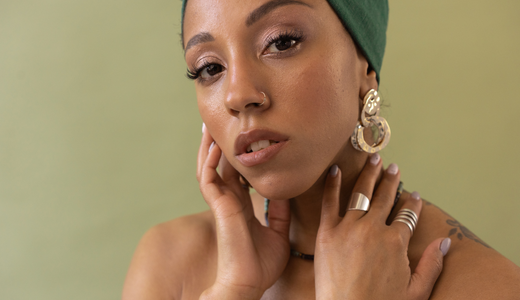 Woman wearing oversized hoop earrings and stacking rings, showcasing bold statement jewelry trends